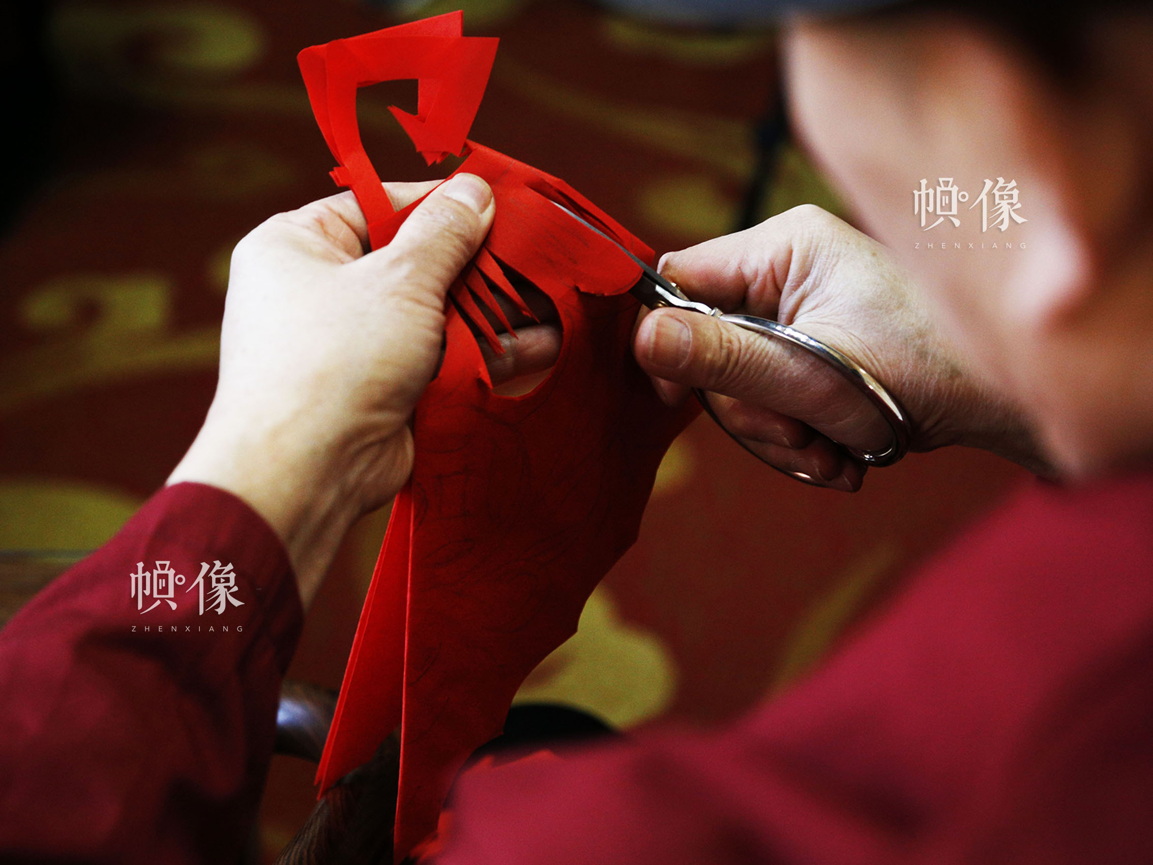 刚刚画好图样的红纸，在姚雨林的手中即将成为一幅窗花作品。中国网实习记者 张钰 摄