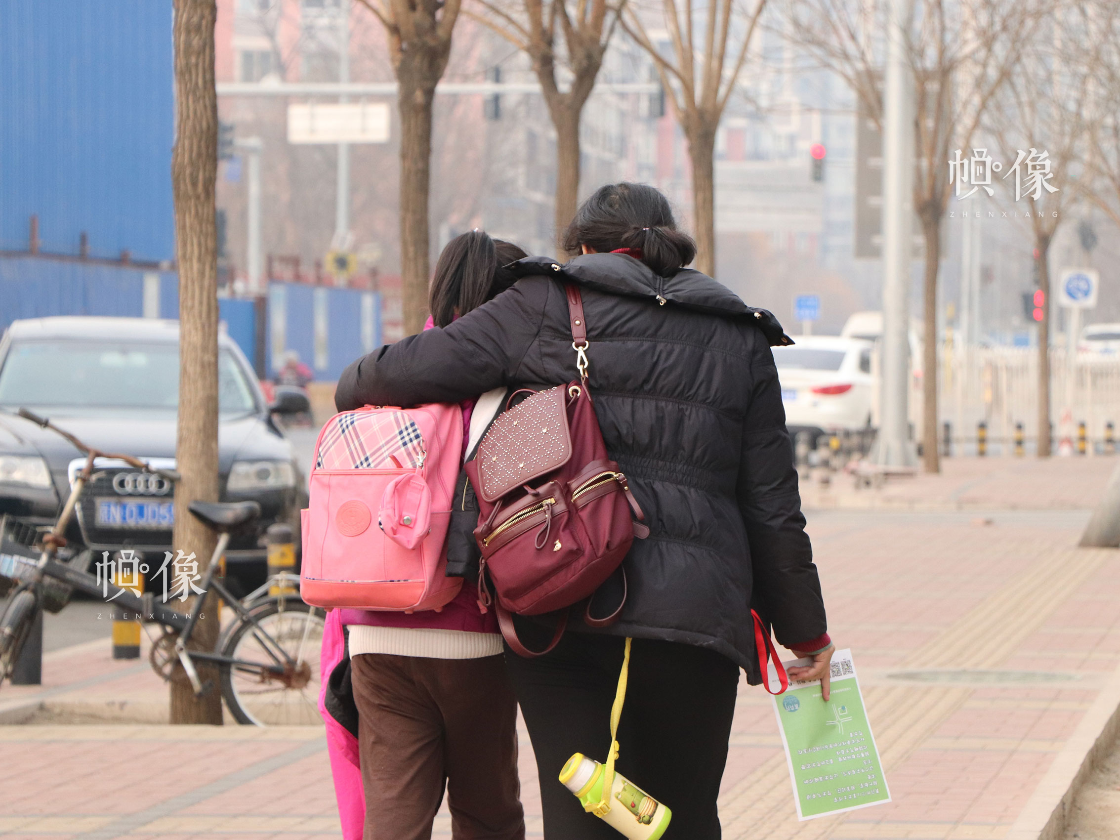 正值學校放學時間，北京豐台區某小學附近，接孩子的家長摟著放學的孩子離開學校。中國網實習記者 韓依 攝
