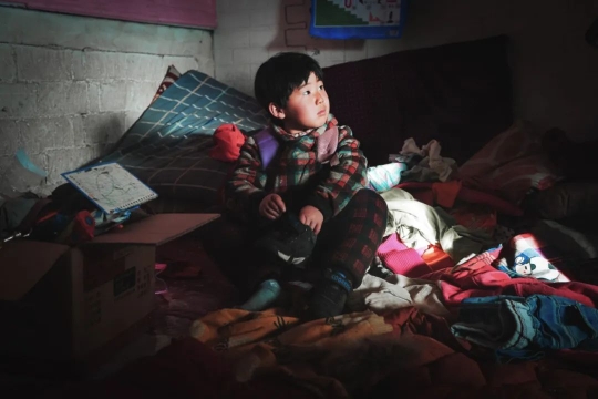 楠楠背着书包蹲坐在炕上看着窗外。