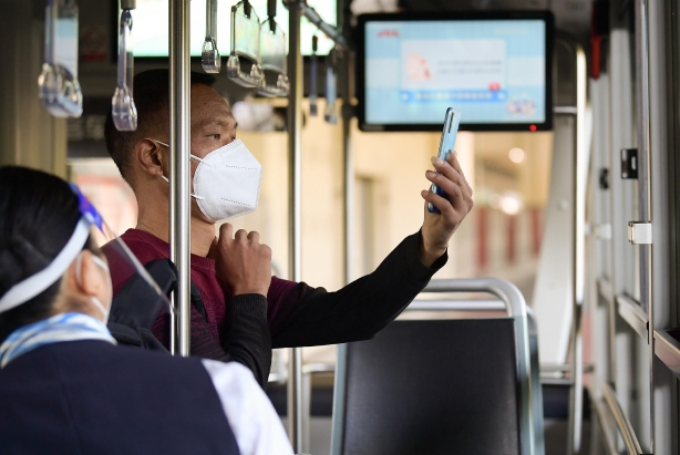 ▲5月22日，上海一名乘客在登车时按规定使用手机扫描公交“场所码”。图/新华社