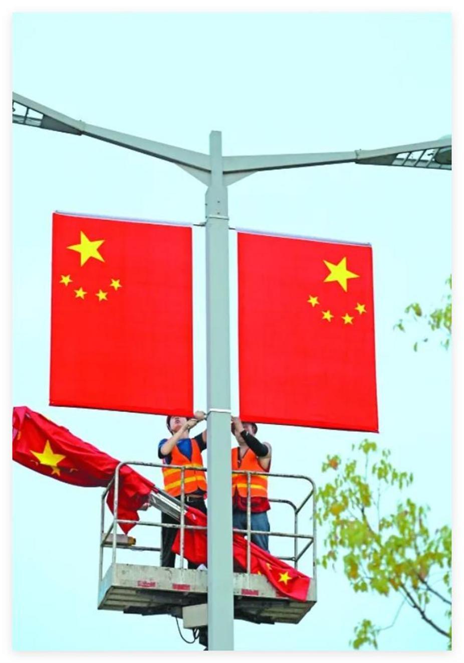 工人在嘉陵区白燕路一段悬挂国旗在滨江中路,鲜红的国旗迎风招展,在