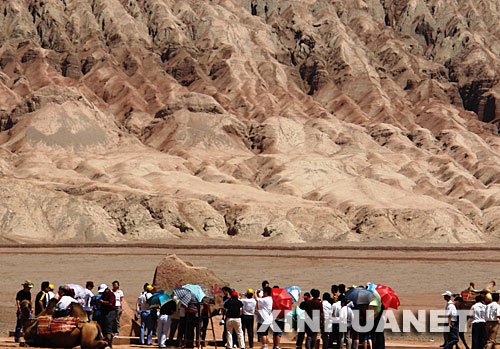 7月30日，游客在新疆吐鲁番火焰山景区游览。 近日，新疆吐鲁番火焰山景区热浪滚滚，但来这里旅游观光的游客仍络绎不绝。据了解，火焰山景区7月日均接待游客超过5000人次。 新华社发（姜晓明 摄） 