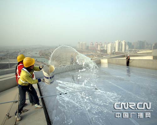 写真：「鳥の巣」の屋上に水をかけて掃除している作業員