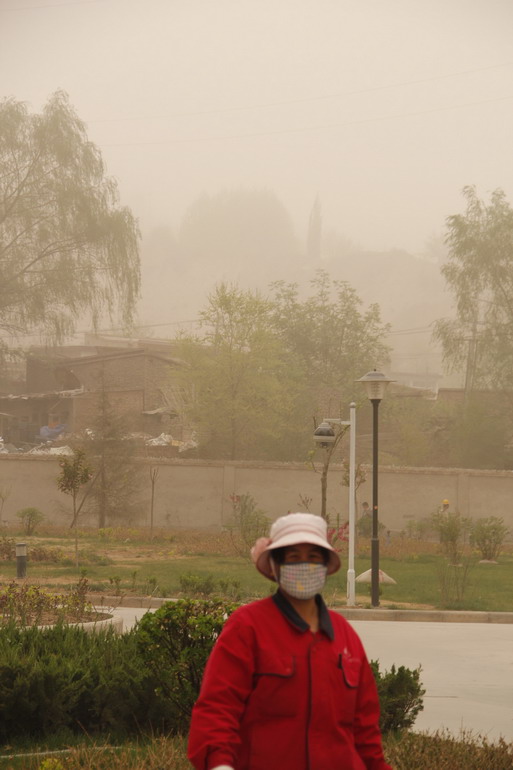 4月29日，在甘肃省永靖县刘家峡镇，一名市民冒着沙尘出行。