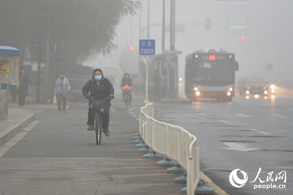 10月11日，市民戴着口罩在大雾行进。（人民网记者翁奇羽 摄）