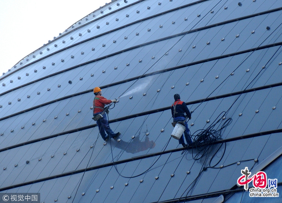 25 февраля, Пекин. В начале весны работники, поддерживающие чистоту, проводят всестороннюю очистку внешней стены Государственного театра Китая, чтобы встретить предстоящее проведение первой сессии ВСНП и ВК НПКСК 13-го созыва в своем наилучшем виде.