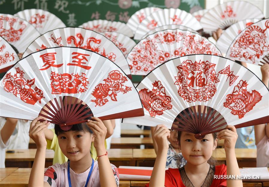 На фото -- за несколько дней до летнего солнцестояния ученики Экспериментальной школы Инаньской зоны экономического развития /провинция Шаньдун, Восточный Китай/ делают традиционные бумажные вееры с аппликациями.