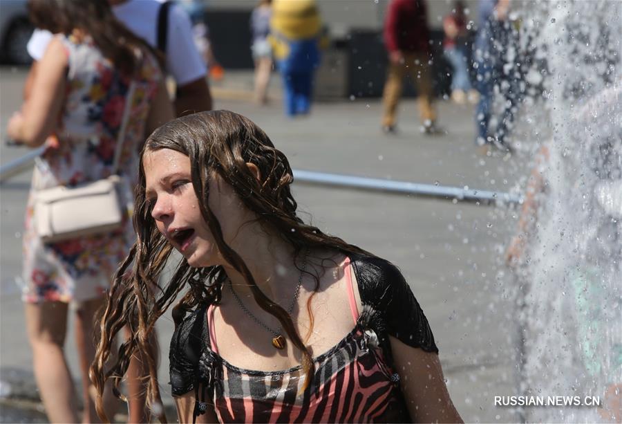Киевляне спасаются от жары возле фонтанов 