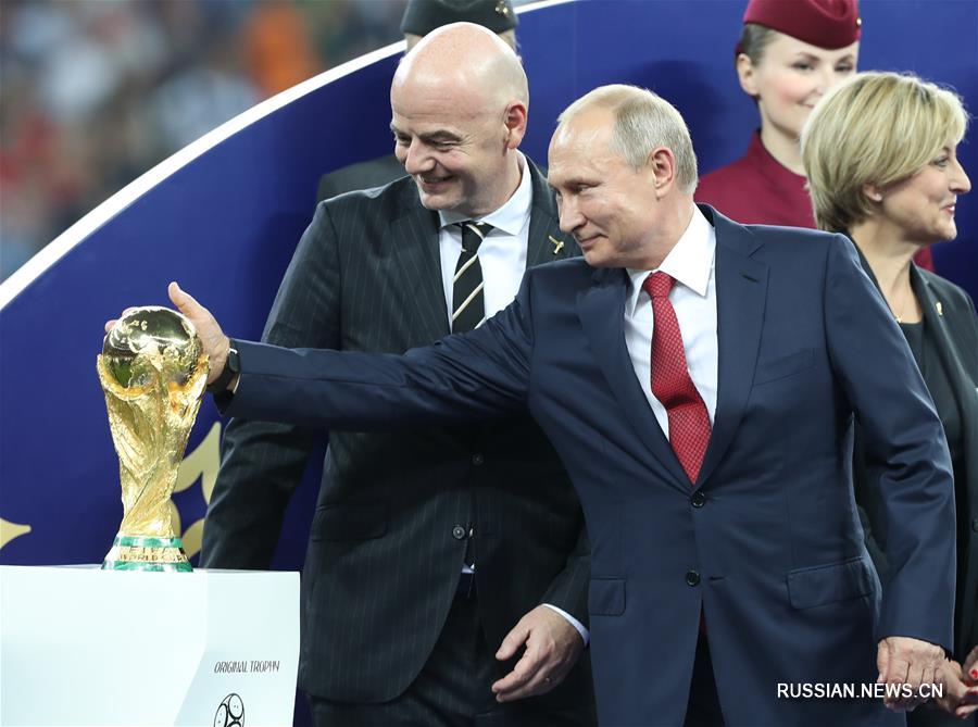 На фото -- во время церемонии награждения президент России Владимир Путин /на переднем плане справа/ погладил Кубок мира. 