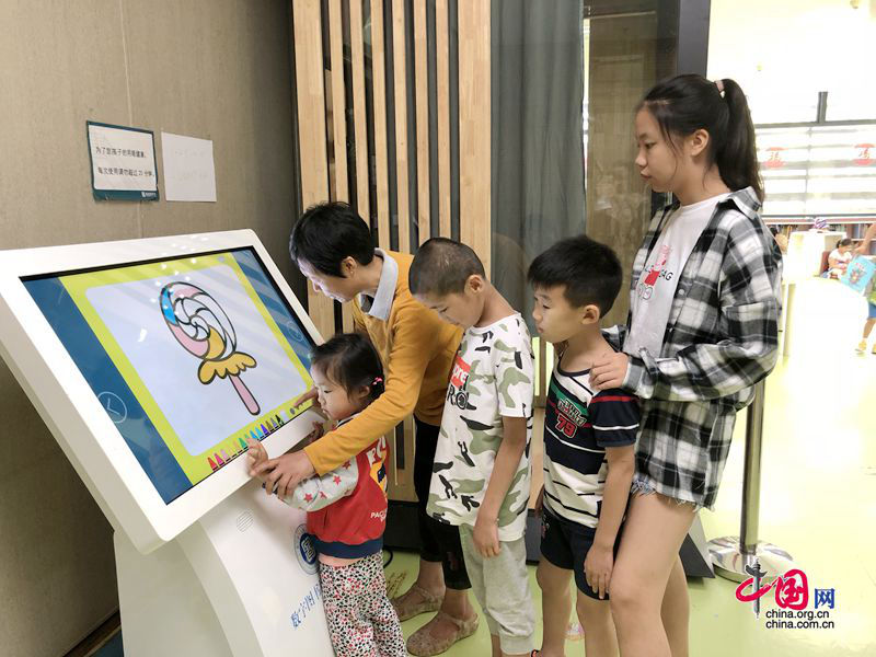 Маленькие читатели стоят в очереди, чтобы раскрасить рисунок на сенсорном экране (Фото: Ли Минъянь)