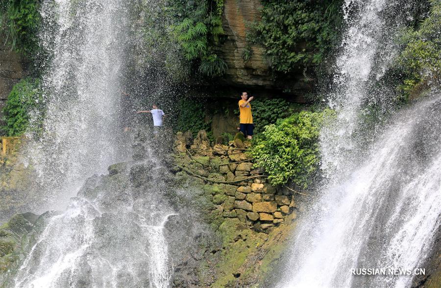 На фото: В поселке Фужун уезда Юншунь Сянси-Туцзя-Мяоского автономного округа провинции Хунань /Южный Китай/ туристы любуются водопадом, наслаждаясь прохладным воздухом.
