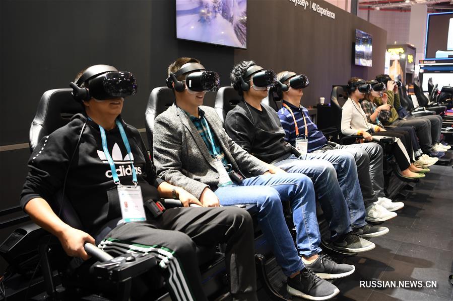 На фото -- посетители на стенде компании Samsung "катаются на лыжах" в шлемах виртуальной реальности. 