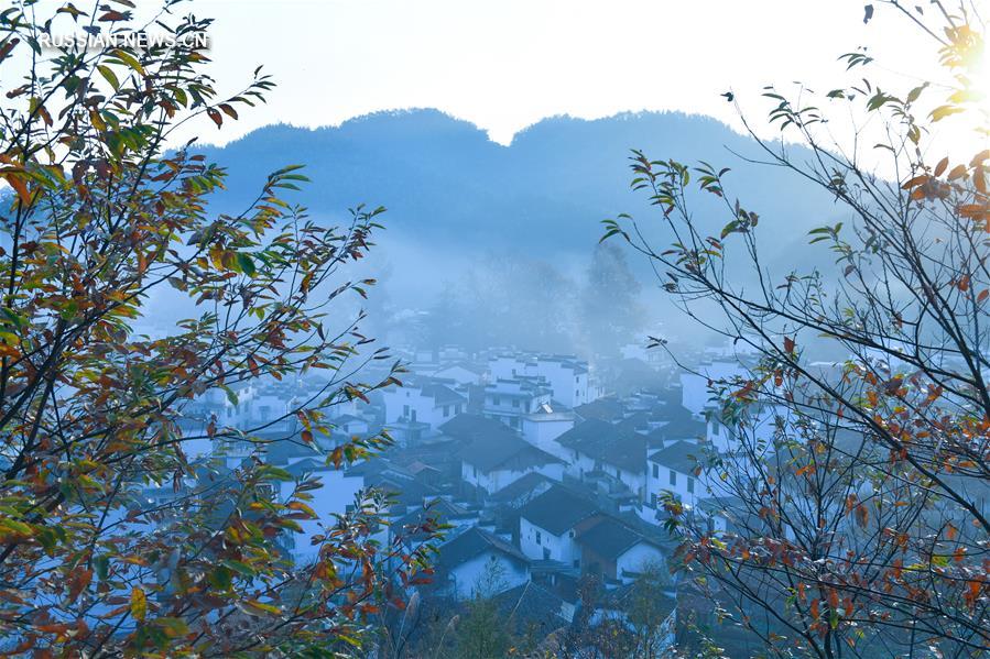 Красные кленовые листья, синий утренний туман, золотые террасные поля -- все краски осени в уезде Уюань провинции Цзянси на востоке Китая. На фото от 6 ноября -- туристы снимают горный пейзаж в деревне Хуанлин поселка Цзянвань. 