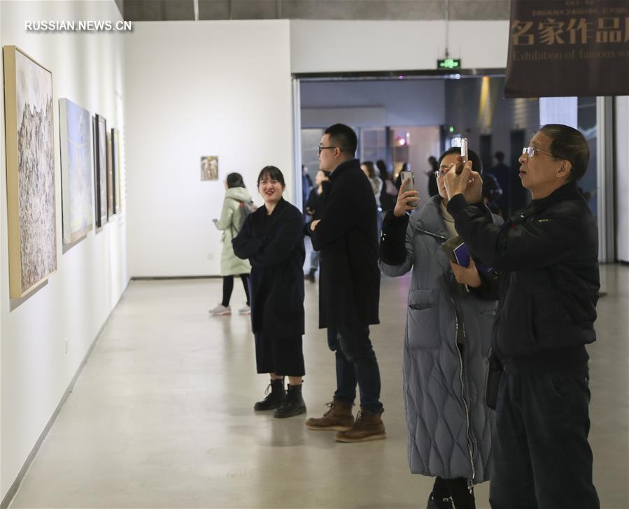На фото -- посетители фотографируют работы известных художников, представленные на выставке. 