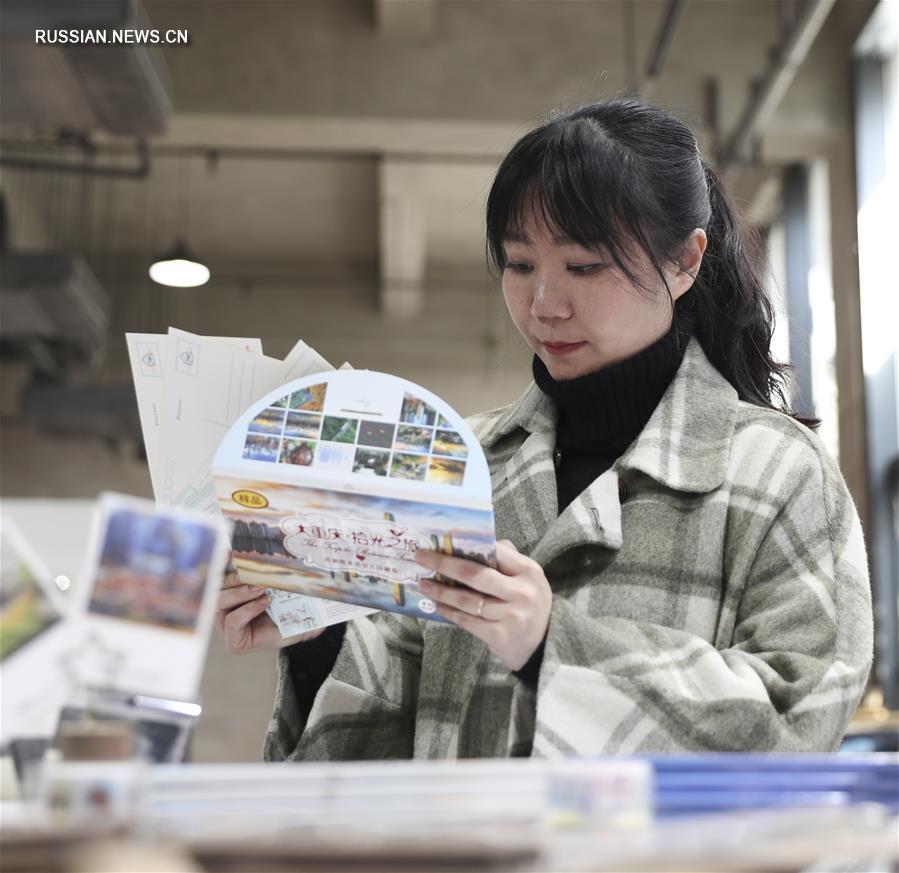 На фото -- посетительница в секции товаров для творчества рассматривает открытки.  