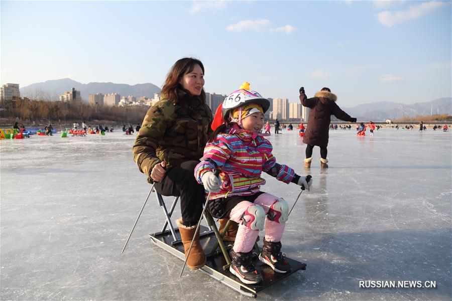 На снимке, сделанном 12 января этого года, люди катаются на одном из катков в районе Мэньтоугоу в Пекине.
