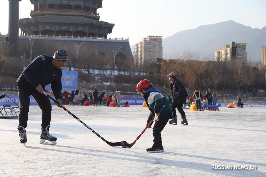 На снимке, сделанном 12 января этого года, люди играют в хоккей на одном из катков в районе Мэньтоугоу в Пекине.