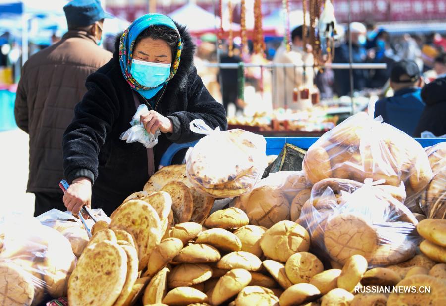 Люди покупают товары на базаре в Синьцзяне