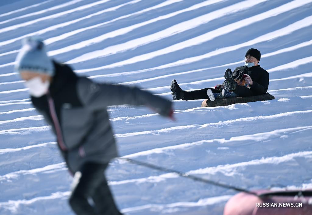 Люди покатаются на сноутюбинге во время ледяного и снежного карнавала, который проводится в парке Таожаньтин в новогодние праздники в Пекине 2 января 2022 года. 