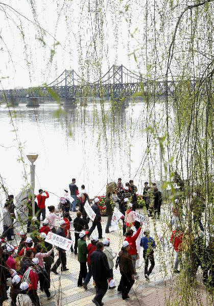 Tourists in the initial package tour group of the Sightseeing on the Liaoning Seashore Avenue promenade to enjoy the scenery of the Yalujiang River in Dandong City, northeast China's Liaoning Province, May 7, 2010. 