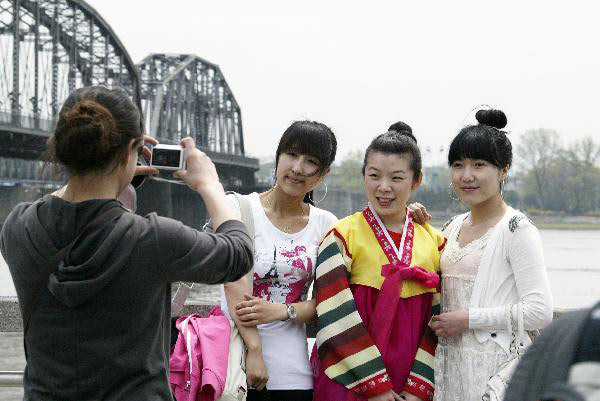 Tourists in the initial package tour group of the Sightseeing on the Liaoning Seashore Avenue promenade to enjoy the scenery of the Yalujiang River in Dandong City, northeast China's Liaoning Province, May 7, 2010. 