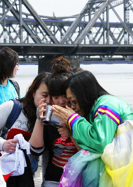 Three girls in the initial package tour group of the Sightseeing on the Liaoning Seashore Avenue review their own video clips of the scenery of the Yalujiang River in Dandong City, northeast China's Liaoning Province, May 7, 2010.