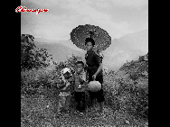A woman and her children come back from the field. In order to shake off poverty, most of the men in Daliang Mountain, Sichuan province go out to work, leaving women to do the farm work. When there is no work at the field, the women will go to fairs to trade farm produce and purchase articles for daily use, or go to the mountain to chop wood, or weave at home... They use their hands to improve their lives.