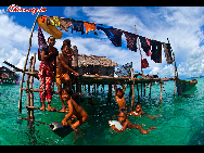 Children play in the water. The Bajau Laut, known as 'the Sea Gypsies,' live at the seaside of Malaysia and the Philippines. They build and live in tatty wooden sheds above the water and make a living by fishing. They have no access to education due to poverty and live on the margins of society.