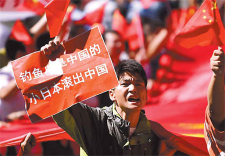 A protester, taking part in a demonstration outside the Japanese embassy in Beijing on Thursday, displays a sign stating that &apos;The Diaoyu Islands belong to China, Japan get out of China&apos;. [China Daily via Reuters]