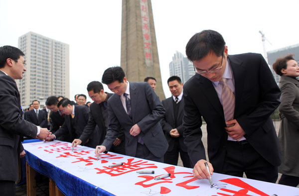 Newly elected officials of Yongchuan district in Chongqing sign their names on a banner and vow to be free from graft in an anti-corruption campaign in front of a monument to honor revolutionary martyrs, earlier this year. [Chen Shichuan/For China Daily]