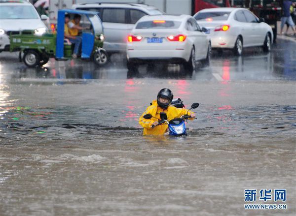 6月1日，市民在江西九江经济技术开发区积水路段推着摩托车涉水前行。当日，江西九江遭受暴雨袭击，九江市城区部分路段积水严重，交通受阻。 [新华社]