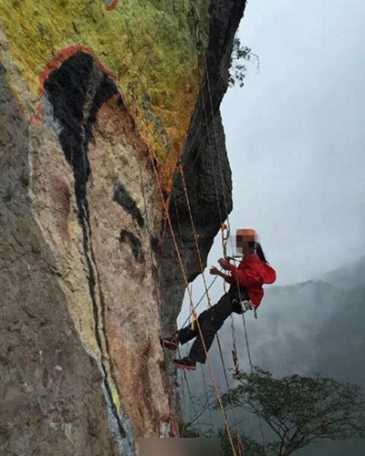 椒江女驴友垂挂到饭蒸岩的峭壁上作画。