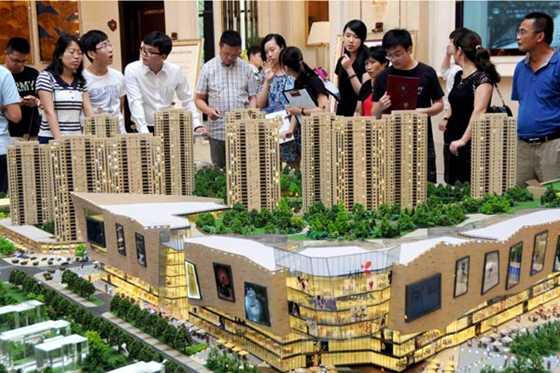 Potential homebuyers examine a property project model in Hangzhou, capital of Zhejiang province, Aug 31, 2014. [Photo/Xinhua]