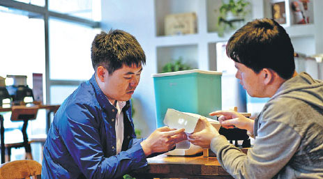 Yang Jian (left) talks with a researcher about how to improve the smart rice storage box, in Shenyang, Liaoning province. [Photo provided to China Daily]