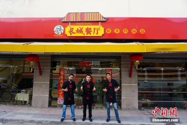 Waiters at Wang Luping&apos;s Chinese restaurant posing for a photo in front of the restaurant in Morocco. [Photo: Chinanews.com] 