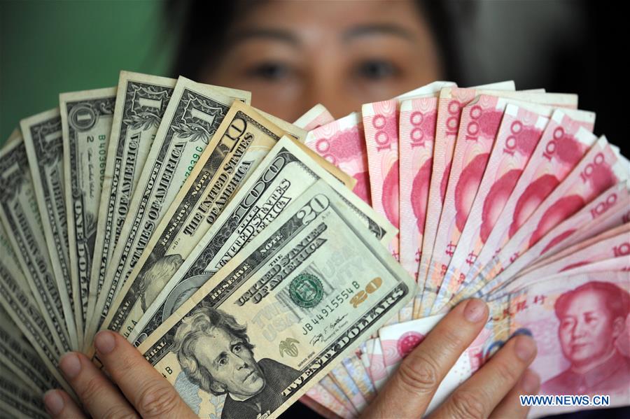 A resident shows China's RMB and US dollar banknotes in Qionghai, south China's Hainan Province, Jan. 7, 2016. [Photo/Xinhua]