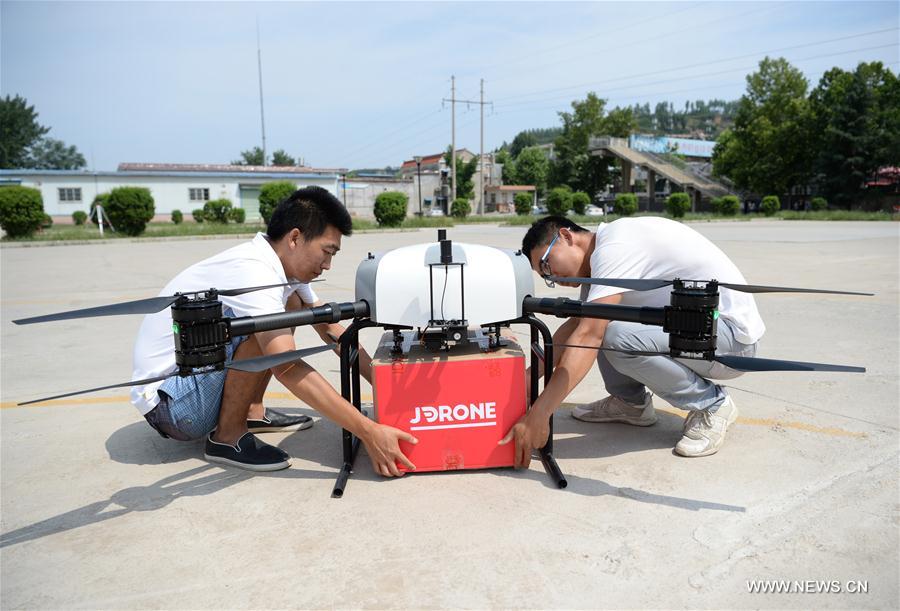Workers prepare to attach a package onto a drone in Xi'an, capital of northwest China's Shaanxi Province, June 20, 2017. Delivering goods to terminal customers through drones has been normalized by JD.com since June 18, 2017 in Xi'an. [Photo/Xinhua]