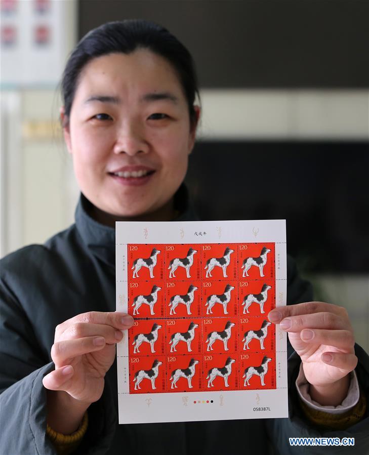 A staff member of China Post presents zodiac stamps for the Year of the Dog in Tancheng County, east China's Shandong Province, Jan. 5, 2018. China Post issued a set of special zodiac stamps for the Year of Dog with two different designs Friday. The Year of Dog, or Chinese traditional lunar New Year of this year, starts from Feb. 16. [Photo/Xinhua]
