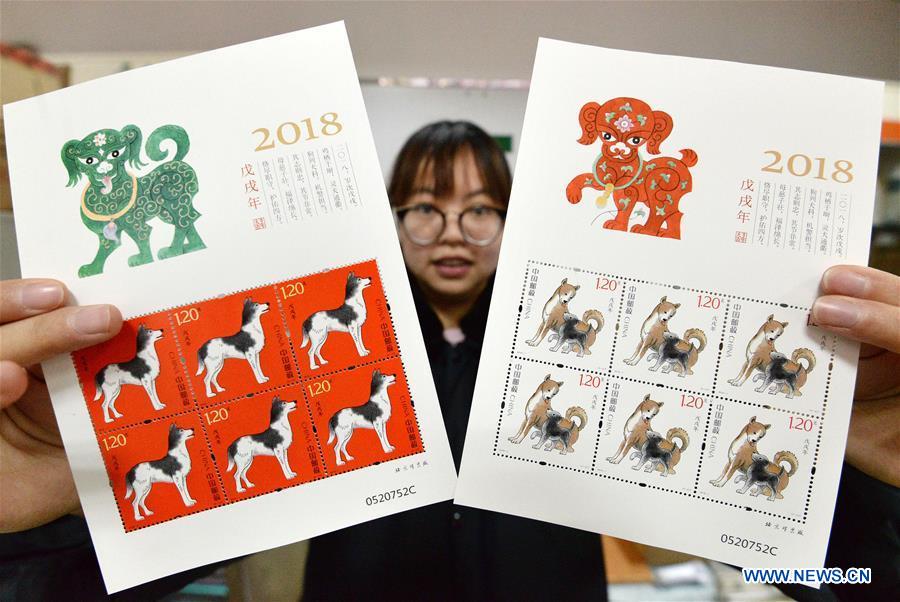 A staff member of China Post presents zodiac stamps for the Year of Dog in Handan, north China's Hebei Province, Jan. 5, 2018. China Post issued a set of special zodiac stamps for the Year of Dog with two different designs Friday. The Year of Dog, or Chinese traditional lunar New Year of this year, starts from Feb. 16. [Photo/Xinhua]