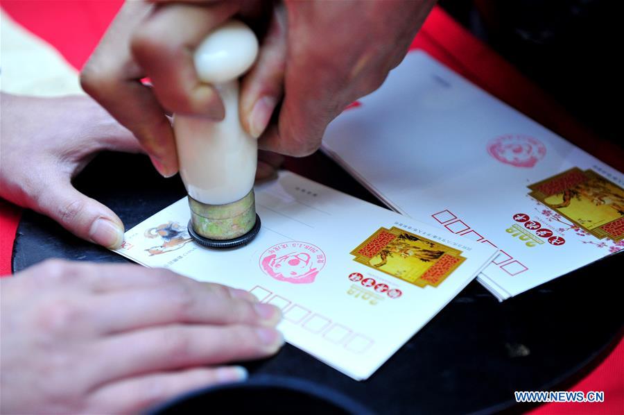 A citizen stamps on a postcard with zodiac stamps for the Year of the Dog in Guiyang, capital of southwest China's Guizhou Province, Jan. 5, 2018. China Post issued a set of special zodiac stamps for the Year of Dog with two different designs Friday. The Year of Dog, or Chinese traditional lunar New Year of this year, starts from Feb. 16. [Photo/Xinhua]