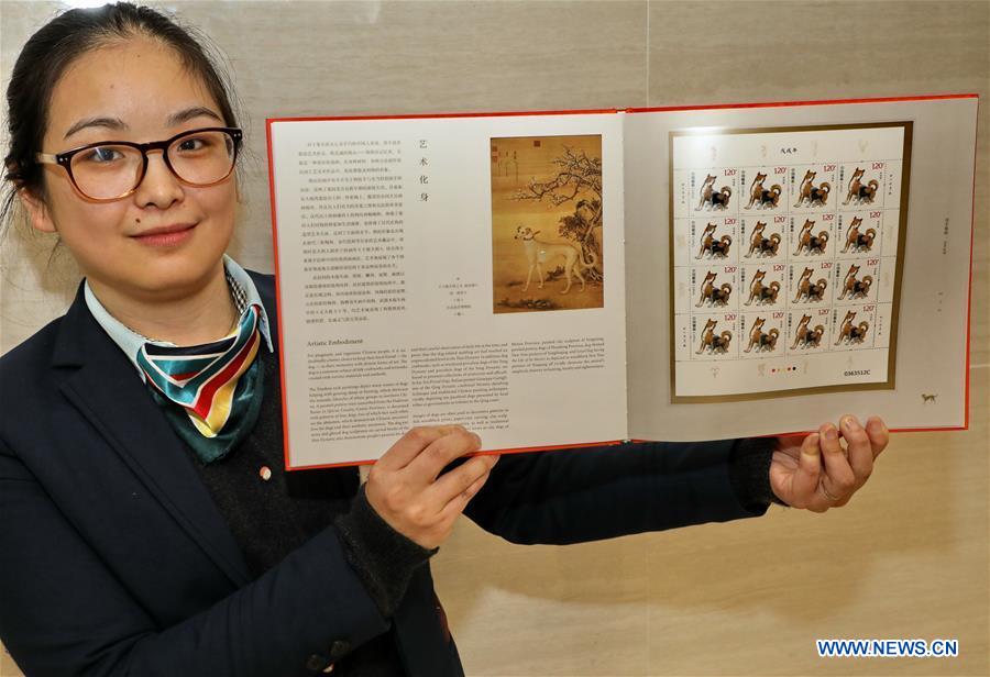 A staff member of China Post presents zodiac stamps for the Year of the Dog in Shanghai, east China, Jan. 5, 2018. China Post issued a set of special zodiac stamps for the Year of Dog with two different designs Friday. The Year of Dog, or Chinese traditional lunar New Year of this year, starts from Feb. 16. [Photo/Xinhua]