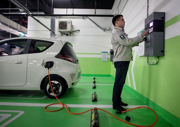 A technician from State Grid Shanghai Municipal Electric Power Co inspects the charging piles, or power ports, in a parking lot before they are put into operation. [Photo/Xinhua]
