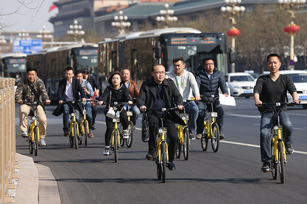 A group of bikers riding ofo bicycles pass by Chang'an Avenue, Beijing, on Mar 10, 2017. [Photo/China Daily] 