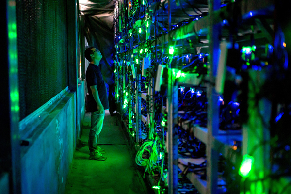 A technician checks mining equipment at a bitcoin mine in Sichuan province. [Photo/China Daily] 