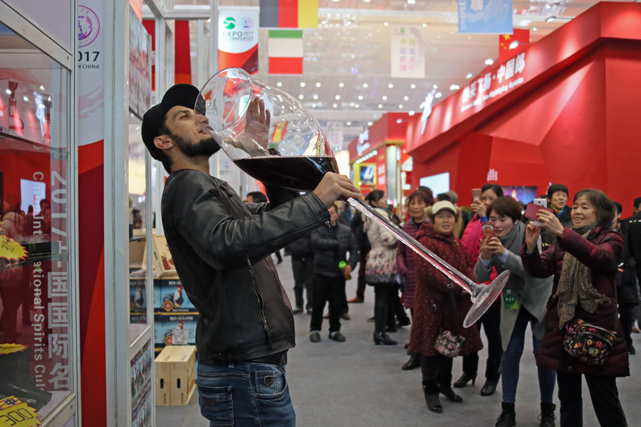 An exhibitor of a wine company drinks from a huge glass to promote sales among visitors at the China International Wine, Beer and Spirits Culture Festival 2017 in Yibin, Sichuan province, in Southwest China. [Photo/China Daily] 