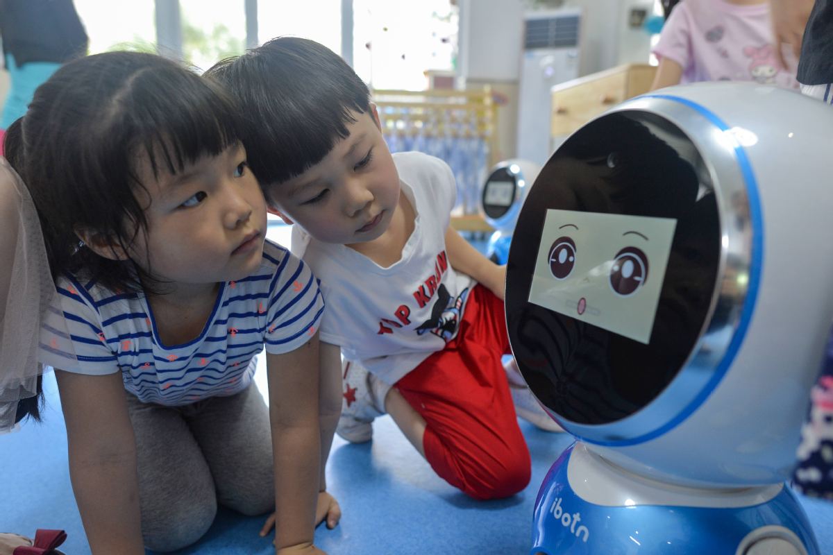Children play with an intelligent robot at a kindergarten in Wuhan, capital of Hubei province. [Photo/China Daily]