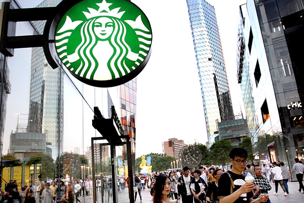 Pedestrians walk past a Starbucks coffee shop in downtown Beijing. [Photo/China Daily]