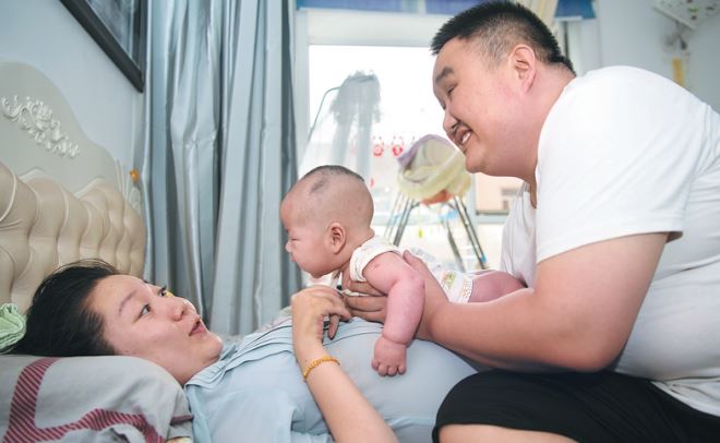 Zhang Yongfei and his wife, Tian Xiao, play with their son at their home. [Photo/China News Service]